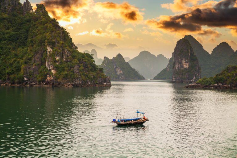 Cruise ships and limestone islands in Vịnh Hạ Long at sunset, Vietnam.