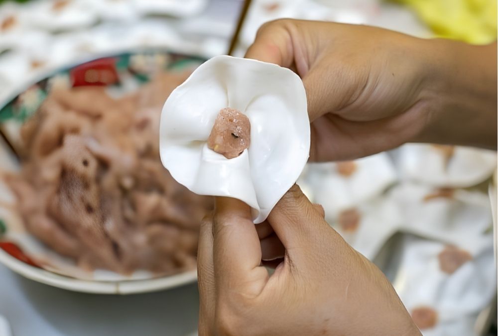 The wrapper is cupped, the filling set in the middle, and the edges pinched in tiny crimps so the dumpling opens like a rose (Source: Collected)